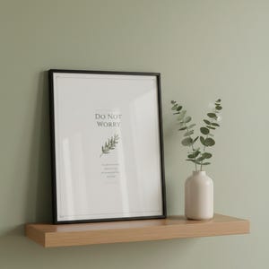 Do Not Worry Matthew 6:34 scripture print in rustic white wood frame on oak console shelf beside ceramic vase with sage eucalyptus stems and dried pampas grass, soft afternoon light, sage bible print botanical christian wall art digital download by TheFramedVerse, elegant bible print gift