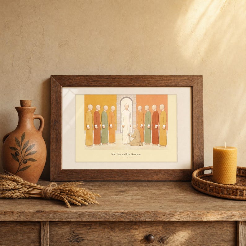 She Touched His Garment Matthew 9:20-22 print in a walnut frame leaning on a rustic wood shelf, styled with a terracotta olive-branch jug, a bundle of dried wheat, a woven tray holding a lit beeswax candle, warm cottage Christian home decor scene, digital download wall art from TheFramedVerse on Etsy