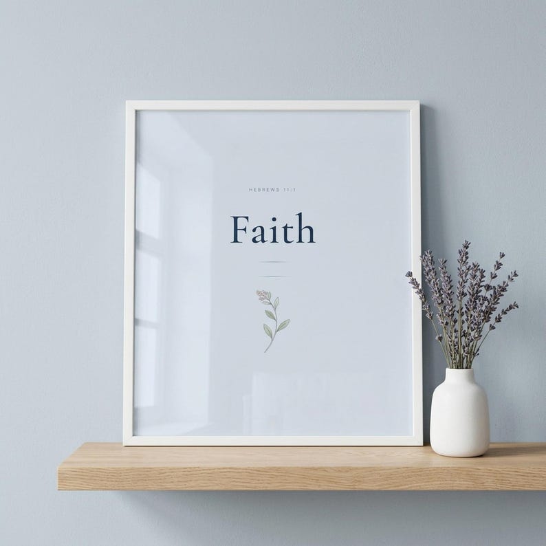 Coquette Christian wall art closeup of Faith Hebrews 11:1 scripture print in blue navy coquette style with delicate botanical illustration, displayed in slim white wooden frame with glass reflection on natural wood shelf with dried lavender in ceramic vase, cool soft natural light