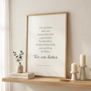 Ecclesiastes 4:9-10 'Two Are Better Than One' Christian wedding wall art in oak frame on floating shelf beside white peonies in ceramic vase, cream linen books, and pillar candles. Romantic Christian newlywed home interior. Perfect wedding gift, anniversary, bridal shower print, instant digital download.