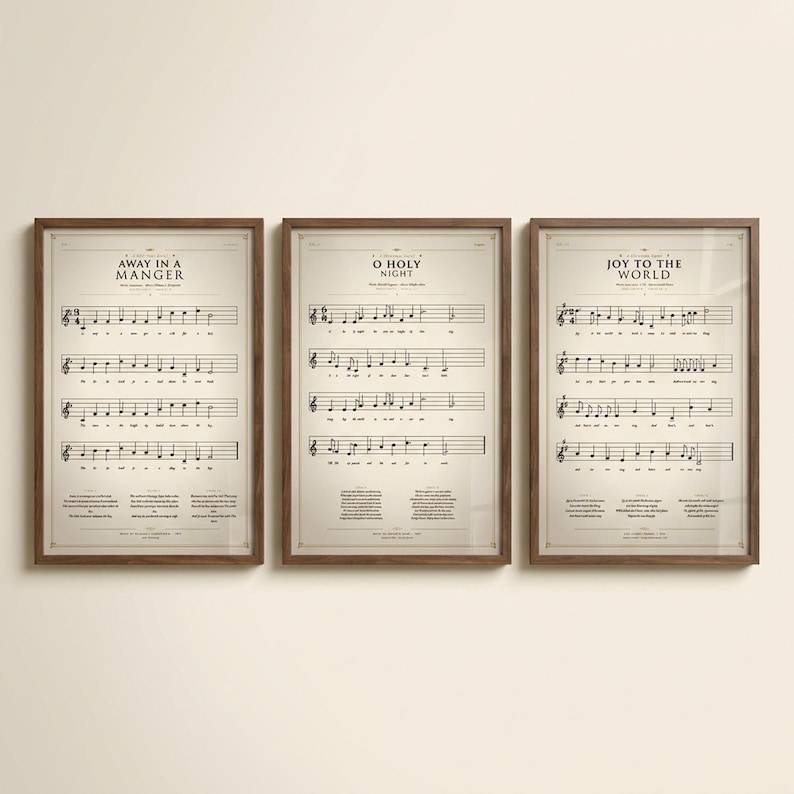 Christmas Hymns Gallery Wall Set of 3 vintage sheet music prints in solid walnut frames, frontal studio shot on cream backdrop, soft top-left key light, glass reflection visible, classical Christmas wall art digital download from TheFramedVerse — Away in a Manger, O Holy Night, Joy to the World hymnal page reproductions