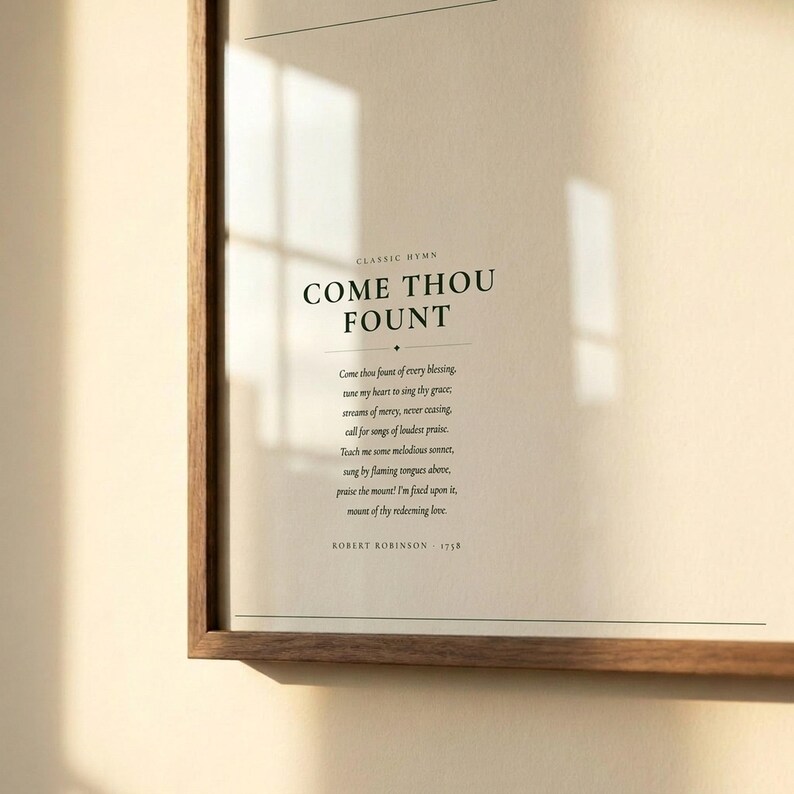 Close-up detail of Come Thou Fount of Every Blessing hymn lyric print in warm walnut float frame with glass and natural golden window light, dark forest green Cormorant Garamond serif typography on warm cream paper, christian hymn song lyric art detail come thou fount art baptism confirmation gift print