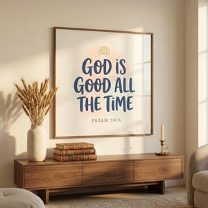 God Is Good All The Time Psalm 34:8 print in walnut frame as living room centerpiece above credenza with dried wheat, vintage books, and brass candle. Premium framed Kids Christian wall art — modern Christian family home aesthetic, perfect for baby dedications, christian gift idea, nursery scripture prints.