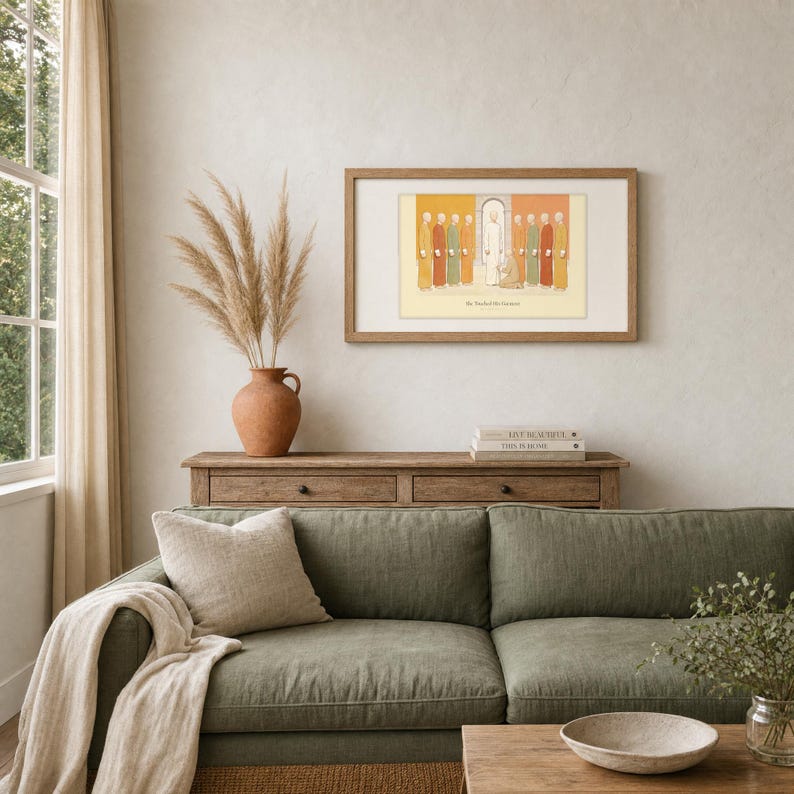 She Touched His Garment Matthew 9:20-22 print in a walnut frame above a rustic wood console, sage green sofa nearby, terracotta vase with dried pampas grass, stacked neutral books, soft natural daylight on a cream textured wall, minimalist Christian home decor, instant digital download from TheFramedVerse on Etsy