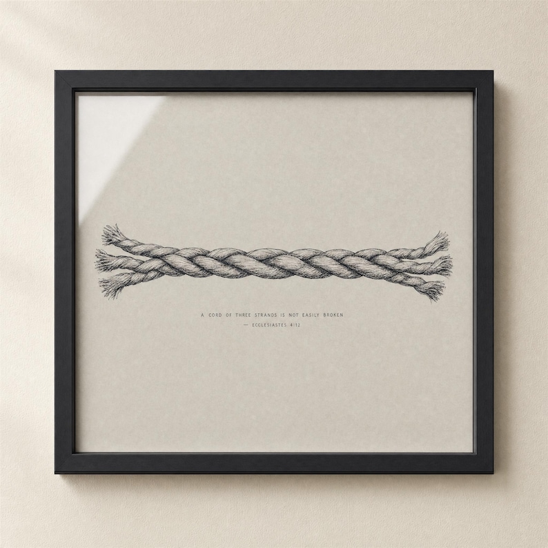 Hero close-up of the Cord of Three Strands wall art print in a matte black frame on a cream plaster wall, glass reflection visible. Hand-lettered Ecclesiastes 4:12 caption on warm grey paper. High-quality digital download for Christian wedding, marriage, or anniversary gift.