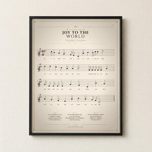 Joy to the World single vintage hymn print in a thin black metal frame, frontal view on an off-white textured wall, modern classical Christmas arrangement with soft top light and gentle shadow. Holiday Christian sheet music wall art digital download from TheFramedVerse, Psalm 98:4 hymnal page in cream and antique sepia.