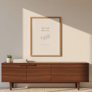 The Lord Bless You Numbers 6 24 26 Nursery Bible Verse Print Christian Wall Art, in gentle sage green nursery design with soft botanical watercolor illustration and calming earth tones, displayed in a bright modern entryway next to a coat rack with natural greenery, serving as welcoming faith-filled home decor