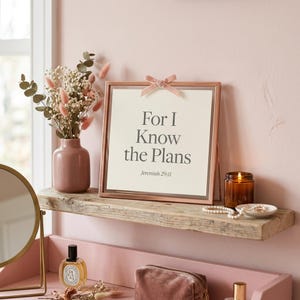 For I Know the Plans I Have for You Jeremiah 29:11 Wall Art Pink Blush Coquette  — hero framed product shot with glass reflection and premium frame. This coquette bow, pink blush christian scripture wall art print features beautiful serif typography on warm cream background. Jeremiah 29:11 bible verse digital download printable for home office bedroom living room gallery wall decor. Perfect chr...