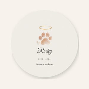 Clean front artwork view of the round acrylic pet memorial ornament without hands, tree branches or decorative props. The Paw with Halo motif is rendered in a soft watercolor style above the personalized name Rocky and the years 2012 to 2024. A plain light background shows the complete front composition, circular shape, ribbon hole and print detail clearly.