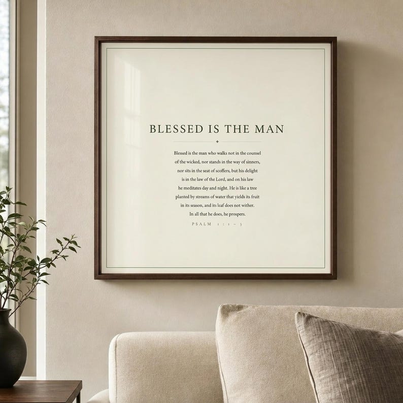 Psalm 1 Blessed Is The Man christian wall art print displayed in a warm sunlit living room. Deep forest green typography on cream background in a walnut wood frame above a linen sofa with neutral throw pillows. Modern minimalist Father's Day scripture gift for faith-driven dads. Psalm 1:1-3 bible verse wall art by TheFramedVerse.