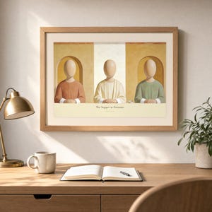 Desk mockup of The Supper at Emmaus in a light oak frame above a wooden workspace with a brass lamp, ceramic mug, open notebook, pen, and leafy plant. The artwork shows Christ seated at the center of a supper table within warm rounded niches. Angled sunlight, neutral styling, and cream matting place the Bible story print in a quiet study or home office setting.