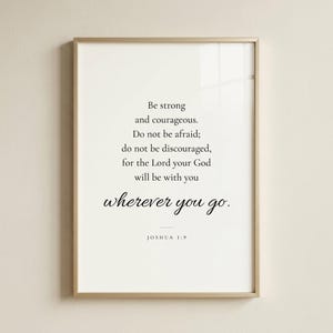 Studio front shot of Joshua 1:9 'Be Strong and Courageous' modern scripture print in refined champagne gold metal frame on soft cream wall. Editorial product photography — Father's Day Christian wall art, confirmation gift, graduation keepsake, baptism gift, men's ministry appreciation print, instant digital download.