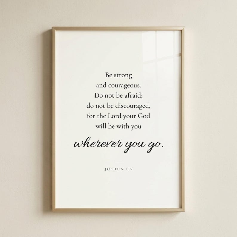 Studio front shot of Joshua 1:9 'Be Strong and Courageous' modern scripture print in refined champagne gold metal frame on soft cream wall. Editorial product photography — Father's Day Christian wall art, confirmation gift, graduation keepsake, baptism gift, men's ministry appreciation print, instant digital download.