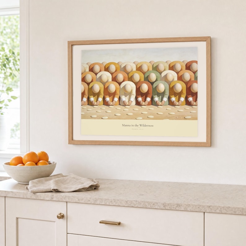 Kitchen mockup of Manna in the Wilderness framed in light oak above a pale stone counter, white cabinetry, a linen cloth, and a bowl of oranges. The artwork shows faceless figures bending to gather pale manna across a warm cream ground. Bright window light and the warm cream mat demonstrate how the Christian print works in a clean, welcoming kitchen interior.