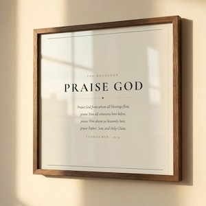 Close-up detail of Doxology Praise God From Whom All Blessings Flow hymn print in warm walnut float frame with glass and natural golden window light, dark forest green Cormorant Garamond serif typography on warm cream paper, christian hymn song lyric art detail doxology wall art print baptism confirmation