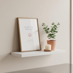 For This Child I Have Prayed 1 Samuel 1:27 nursery wall art print with a soft pink peony in minimalist typography. Framed in wood on a white floating shelf with eucalyptus and a candle. Christian nursery decor, baby shower or baby dedication gift for a new mom. Instant digital download printable.