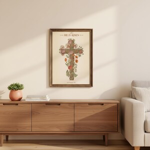 William Morris He is Risen Cross Print – Floral Easter Christian Decor, — "He is not here; He has risen, just as He said", in vintage William Morris Arts and Crafts botanical style with ornate floral border on aged cream parchment, displayed in a beautifully styled modern living room above a warm wooden sideboard with soft natural light creating gentle shadows on the frame