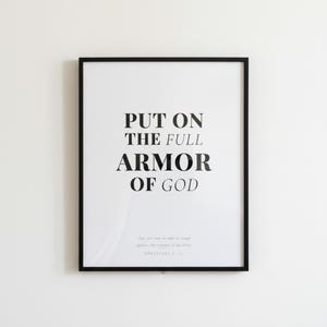 Ephesians 6 Wall Art Put on the Full Armor of God Scripture Print Christian Boys, in contemporary bold serif typography in black on clean white background, styled on a wooden floating shelf next to a ceramic vase with dried eucalyptus, creating a warm and inviting Christian home decor vignette