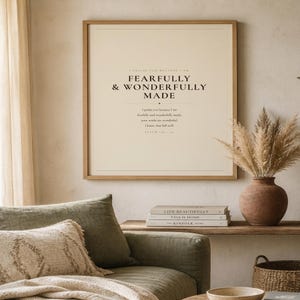 Warm lifestyle room with the framed design on a soft cream wall beside neutral decor and natural window light. The Fearfully and Wonderfully Made artwork uses minimalist boho typography in beige, brown, and black. This Psalm 139:14 print suits a nursery, baptism gift, baby dedication, bedroom, or quiet Christian reading corner as printable digital wall art.