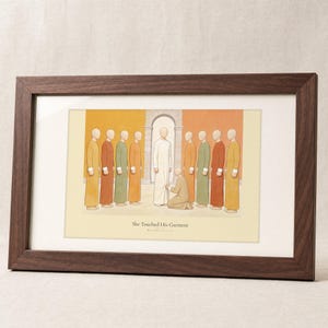 She Touched His Garment Matthew 9:20-22 print in a solid walnut frame with a cream mat, frontal studio shot on a soft linen backdrop, gentle diagonal window light crossing the glass, e-commerce hero photograph of biblical wall art, modern scripture illustration, Christian digital download by TheFramedVerse on Etsy