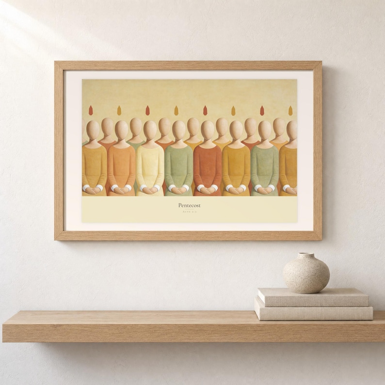 Shelf mockup of Pentecost in a light oak frame resting on a pale wood surface beside stacked neutral books and a rounded ceramic vase. The framed print shows a row of faceless apostles standing shoulder to shoulder, each with a small flame above the head. Cream matting, soft wall texture, and natural light present the horizontal Bible artwork at an easy domestic scale.