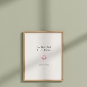 For This Child I Have Prayed 1 Samuel 1 27 Nursery Wall Art Bible Verse Print, in gentle sage green nursery design with soft botanical watercolor illustration, calming earth tones and tender serif typography, styled on a nursery shelf with baby books, a wooden cross and dried flowers, creating a sweet faith-filled vignette that grows with your child