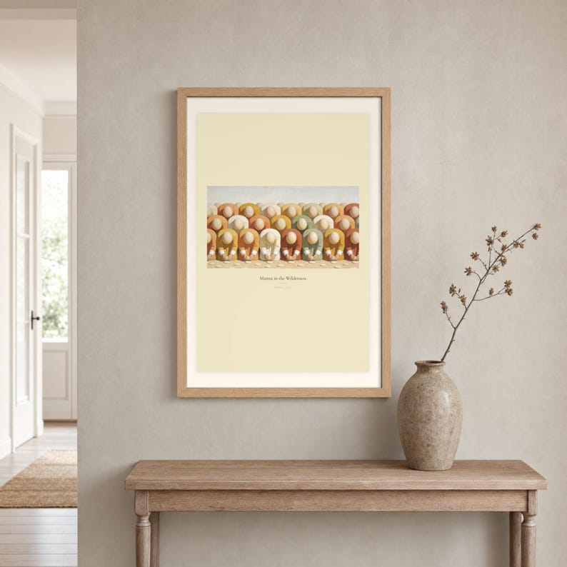 Room mockup of Manna in the Wilderness displayed in a light oak frame on a warm neutral wall. The landscape artwork shows faceless figures bending to gather pale manna across a warm cream ground. A wide cream mat and restrained fresco palette suit a calm living room, prayer space, or Christian home. The printed title and Exodus 16:15 remain visible beneath the image.