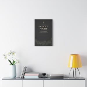 Golden stars surround elegant cream O Holy Night serif lettering on textured charcoal paper, with shadowy evergreen trees forming a deep lower border. Inspired by the beloved Christmas carol and Luke 2:11, this dark vintage typography artwork in black, cream, and gold is printed on stretched canvas. This angled product view shows the gallery wrapped edge clearly.