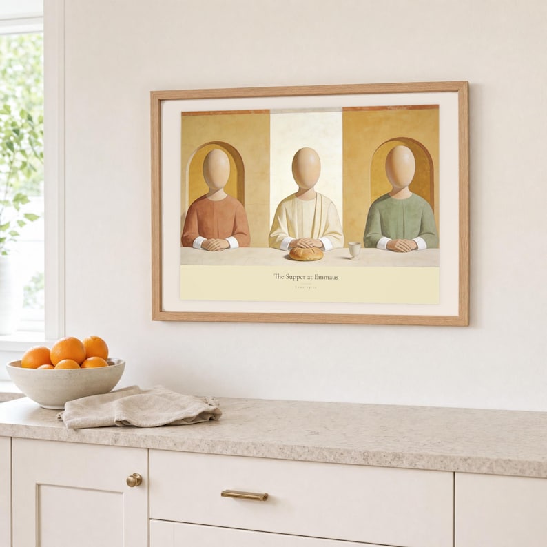 Kitchen mockup of The Supper at Emmaus framed in light oak above a pale stone counter, white cabinetry, a linen cloth, and a bowl of oranges. The artwork shows Christ seated at the center of a supper table within warm rounded niches. Bright window light and the warm cream mat demonstrate how the Christian print works in a clean, welcoming kitchen interior.