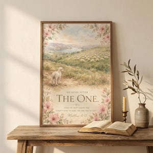 He Goes After the One Matthew 18:12 watercolor christian wall art leaning on a rustic console table beside an open vintage Bible, brass candlestick, and dried olive branch. Reverent ninety and nine parable styling — baptism gift, christian gift idea, scripture home decor. Digital download.