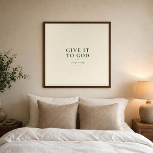 Give It To God and Go To Sleep bedroom wall art in walnut frame above white linen bed. Dark forest green typography on warm cream. Modern farmhouse christian bedroom decor. Printable digital download by TheFramedVerse.