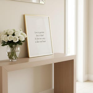 Love Is Patient Love Is Kind 1 Corinthians 13:4 Wall Art Christian Wedding, — "Love is patient, love is kind. It does not envy, it does not boast", in romantic wedding typography with elegant calligraphy, delicate gold ornamental accents on warm blush background, photographed in detailed close-up view showing the premium glass frame, crisp typography and intricate artistic details that make