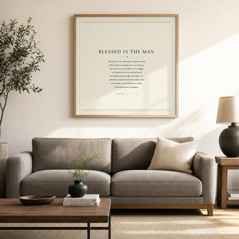 Wide lifestyle shot of a neutral living room featuring Psalm 1 Blessed Is The Man framed scripture print as the central wall art above a grey linen sofa. Deep green and cream minimalist design anchors the room with quiet faith. Christian wall art for men, printable Father's Day gift. Psalm 1:1-3 bible verse print by TheFramedVerse.
