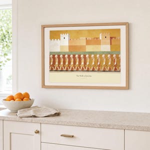 Kitchen mockup of The Walls of Jericho framed in light oak above a pale stone counter, white cabinetry, a linen cloth, and a bowl of oranges. The artwork shows a fortified ochre city above a passing line of faceless horn bearers. Bright window light and the warm cream mat demonstrate how the Christian print works in a clean, welcoming kitchen interior.