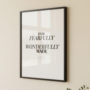 Psalm 139 14 Wall Art Fearfully and Wonderfully Made Scripture Print Nursery, — "I praise you because I am fearfully and wonderfully made; your works are wonderful", in gentle sage green nursery design with soft botanical watercolor illustration and calming earth tones, photographed in beautiful close-up detail showing the premium glass frame reflection