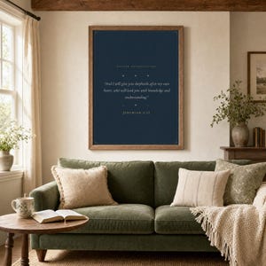 Jeremiah 3:15 Shepherds After My Own Heart print framed in light oak above a cream linen reading chair with knit throw, open leather Bible and ceramic mug on side table, soft warm afternoon window light, minimalist farmhouse christian home decor, pastor appreciation wall art instant digital download from TheFramedVerse Etsy shop