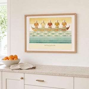Kitchen mockup of The Great Catch of Fish framed in light oak above a pale stone counter, white cabinetry, a linen cloth, and a bowl of oranges. The artwork shows faceless fishers lifting a broad net filled with sage fish beside a wooden boat. Bright window light and the warm cream mat demonstrate how the Christian print works in a clean, welcoming kitchen interior.
