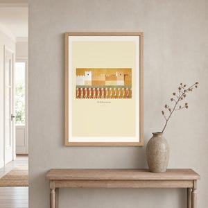 Room mockup of The Walls of Jericho displayed in a light oak frame on a warm neutral wall. The landscape artwork shows a fortified ochre city above a passing line of faceless horn bearers. A wide cream mat and restrained fresco palette suit a calm living room, prayer space, or Christian home. The printed title and Joshua 6:20 remain visible beneath the image.