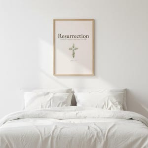 He is Risen Easter Wall Art, Floral Cross Scripture Print, in beautiful floral cross composed of spring roses, greenery and wildflowers, hanging above a cozy bed in a peaceful bedroom setting, creating an inspiring and calming atmosphere for morning devotions and evening prayer. Instant digital download printable wall art in multiple sizes for easy home printing