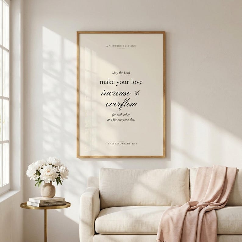 1 Thessalonians 3:12 'May the Lord Make Your Love Increase and Overflow' modern Christian wedding wall art print framed in light oak above a cream linen sofa, terracotta vase with dried pampas grass on console, soft natural daylight, minimalist farmhouse Christian newlywed home decor, instant digital download from TheFramedVerse on Etsy
