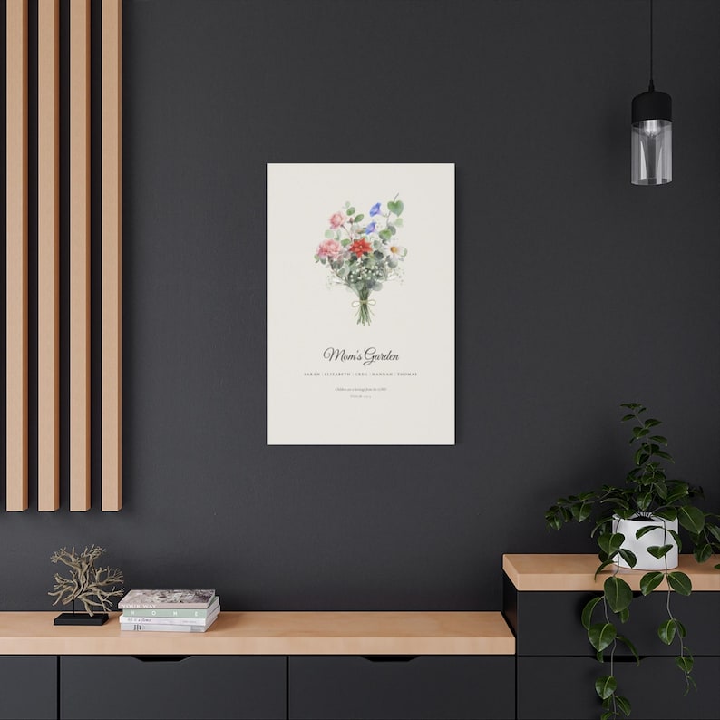 Second Printify lifestyle context showing the personalized birth flower canvas displayed in a bright modern room. Watercolor blooms represent each family member, with individual names, a custom title and optional Psalm 127:3 wording. The square view helps buyers picture the physical 16x20 stretched canvas as ready to hang wall decor and a thoughtful canvas gift for mom or grandma.
