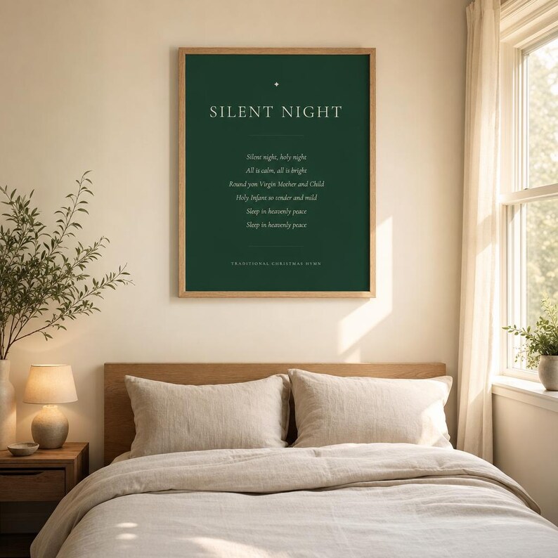 Framed Silent Night Christmas print hanging above a beige sofa with soft neutral cushions. The deep forest green artwork features cream serif lettering, a gold star ornament, the centered first verse, and a Traditional Christmas Hymn footer. This serene minimalist holiday print adds classic Christmas hymn wall art to a calm, welcoming living room.