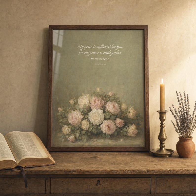 Grace Is Sufficient 2 Corinthians 12:9 vintage oil painting print framed in rustic walnut wood, leaning on a weathered oak console table next to an open vintage leather bible, antique brass candlestick with lit beeswax candle, terracotta pot with dried lavender, cottage editorial reverent Christian-faith home decor, TheFramedVerse digital download
