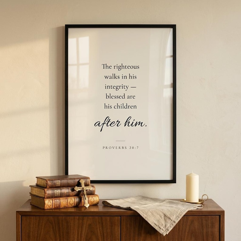 Proverbs 20:7 'The Righteous Walks in Integrity' Christian wall art in modern minimalist serif typography on cream, framed in matte black above a classic entryway console with leather Bible and brass candlestick. Premium Father's Day digital download, gift for Christian dads, grandfathers, men's ministry leaders.