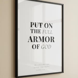 Ephesians 6 Wall Art Put on the Full Armor of God Scripture Print Christian Boys, — "Put on the full armor of God so that you can take your stand against the devil's schemes", in contemporary bold serif typography in black on clean white background, presented as an elegant flat lay on white marble with a fountain pen and eucalyptus sprig, showing the complete print design in full detail