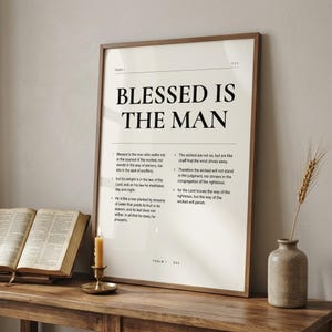 Psalm 1 'Blessed Is The Man' framed print leaning on a rustic wooden console next to an open vintage leather Bible, brass candlestick with lit beeswax candle, and stoneware vase with dried wheat. Reverent Christian masculine home decor, Father's Day gift, printable from TheFramedVerse on Etsy.
