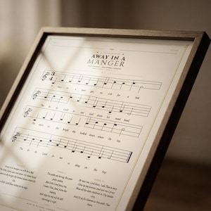 Extreme close-up macro of Away in a Manger vintage hymnal print on premium archival matte paper — showing aged sepia paper texture, 1900s-era sheet music typography, ink saturation and crisp letterpress detail, no props, editorial product shot, Christmas carol wall art digital download by TheFramedVerse on Etsy