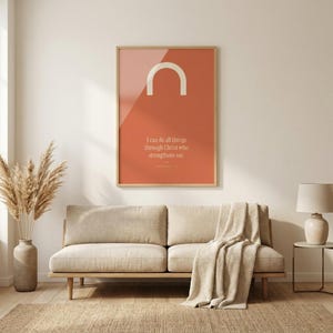 Philippians 4:13 I can do all things through Christ trendy christian wall art in oak glass frame above linen sofa in scandinavian living room. Coral red modern maximalist bible verse print with cream arch shape, pampas dried flowers, jute rug. Part o