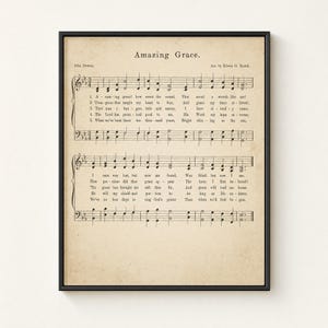 Amazing Grace vintage sheet music wall art framed frontal in a slim matte black metal frame on a warm cream limewashed plaster wall. Aged hymnal page with John Newton 1779 hymn notation, perfect Christian farmhouse home decor, instant digital download from TheFramedVerse on Etsy.