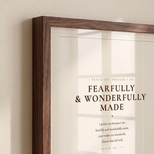 Close up detail of the framed artwork, highlighting the crisp lettering, paper texture, fine lines, and subtle glass reflection. The Fearfully and Wonderfully Made artwork uses minimalist boho typography in beige, brown, and black. This Psalm 139:14 print suits a nursery, baptism gift, baby dedication, bedroom, or quiet Christian reading corner as printable digital wall art.